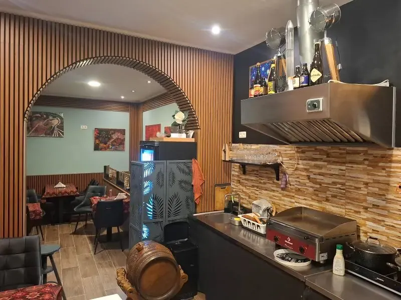 La salle de Konaku : arche en bois, tables dressées et coin grillades